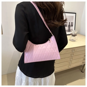 Sac sous le bras rose matelassé avec surpiqûres losanges porté par un mannequin