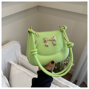 Detail of green handheld bag with golden metal bow and stylish knotted rope handle