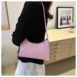 Sac baguette rose matelassé en similicuir avec zip doré porté par le mannequin