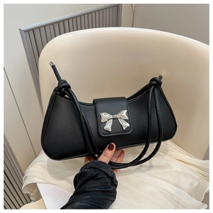 Detail of a black French baguette bag with a silver bow clasp and knotted strap details