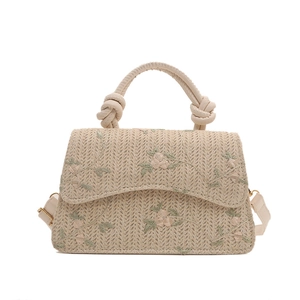 Beige woven crossbody bag with floral embroidery and adjustable leather shoulder strap