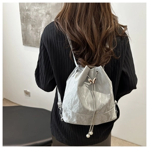 Detail der silbernen Beuteltasche mit Schmetterlingsverschluss und Perlen-Kordelzug