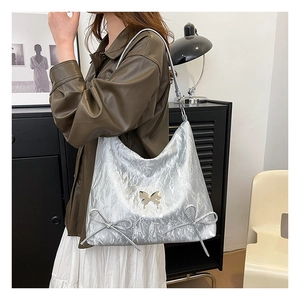 Dettaglio borsa hobo argento metallizzato con farfalla cromata e texture plissettata