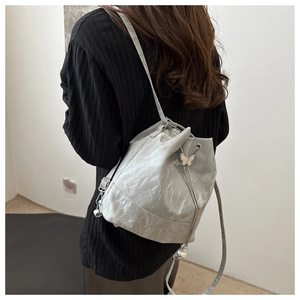Detail der silbernen Metallic-Beuteltasche mit Schmetterlings- und Perlenanhängern