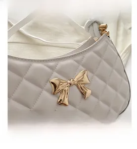 Vue détaillée du sac matelassé blanc avec boucle nœud en métal doré et fine bandoulière