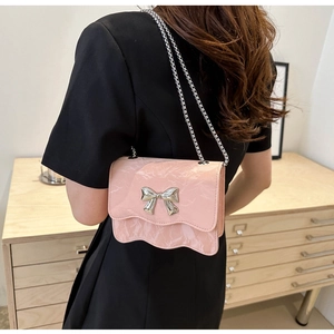 Rosa Umhängetasche mit Marmormuster, silberner Schleife und Wellenrand am Modell