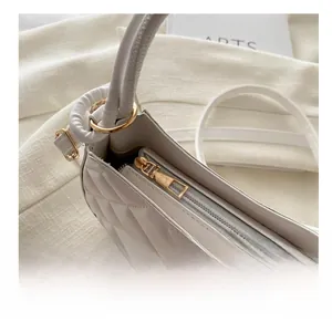 Gros plan du zip doré fluide et du cuir matelassé blanc sur le sac en croissant