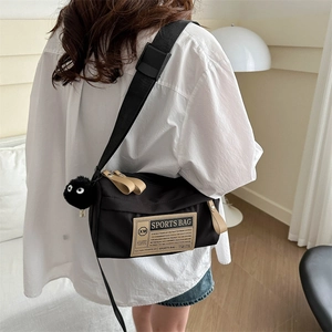 Casual black nylon crossbody sports bag with soot sprite charm and adjustable shoulder strap