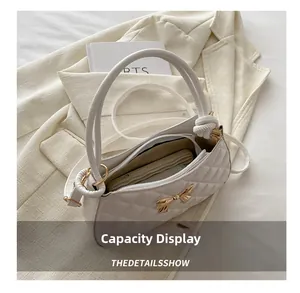Détail de l'intérieur d'un sac blanc matelassé avec décoration de papillon doré chic