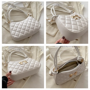 Détail du sac demi-lune blanc matelassé avec nœud papillon doré et bandoulière réglable