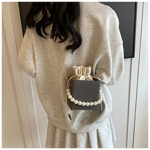 Detail of square bucket bag with large pearl handle and elegant gold chain strap
