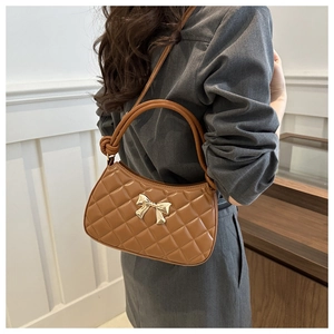 Détail d'un sac demi-lune marron matelassé avec boucle papillon dorée et bandoulière nouée