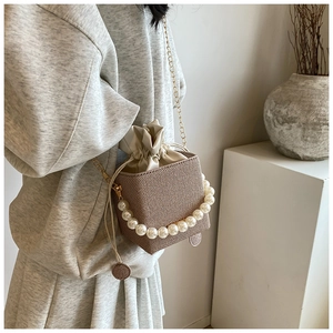 Detail of woven bucket bag with pearl handle and leather drawstring closure