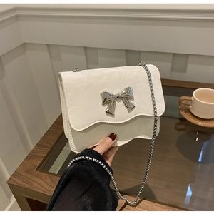 Detail der weißen Schmetterlings-Handtasche mit Wellenkanten und silberner Kette