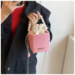 Pink woven bucket bag with pearl handle, silk drawstring inner and gold chain detail
