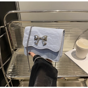 Detail der hellblauen Plissee-Handtasche mit silberner Schmetterlingsschnalle und Metallkette