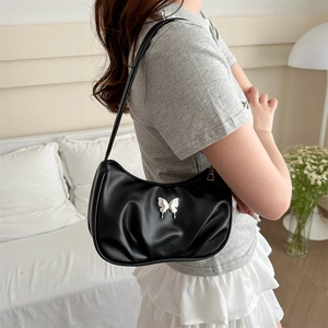 Sac hobo noir minimaliste avec papillon argenté présenté dans une scène de vie