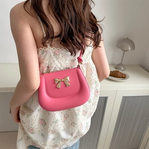 Pink PU leather handbag for women featuring a gold metal bow and thin shoulder strap