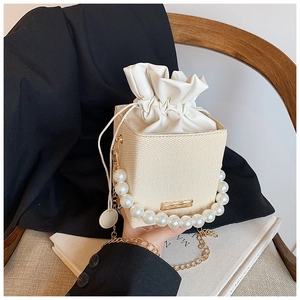 Detail of straw woven box bag with faux pearl handle and white drawstring closure
