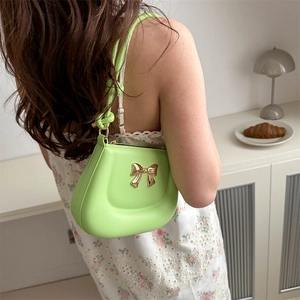 Chic lime green leather handbag with golden bow detail shown in a lifestyle setting