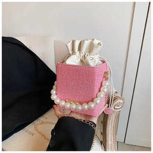 Close-up of pink woven bucket bag with pearl handle and white drawstring liner