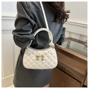 Détail du sac croissant matelassé blanc avec boucle papillon dorée porté à l'épaule