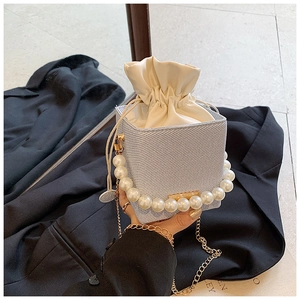 Detail of light blue bucket bag featuring large pearl handle and gold chain strap