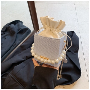 Detailed shot of light blue textured bucket bag with pearl handle and golden chain