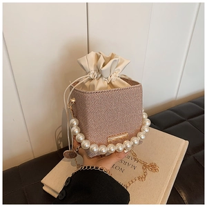 Detail of woven bucket bag with pearl handle, gold chain and secure drawstring closure