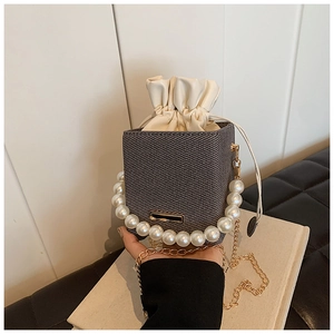 Close-up of woven bucket bag with large pearl handle and drawstring inner pouch