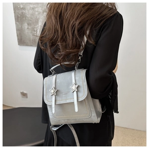 Silver-grey small fashion backpack with star buckles shown on a model's back