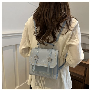 Detail of light blue PU leather backpack with star buckles and golden stitching on back