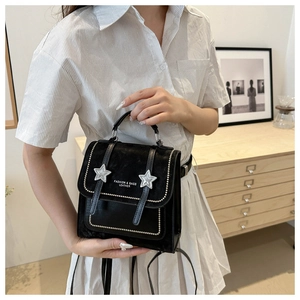 Detail of suede-texture black backpack with silver star motifs and pearl rivet accents