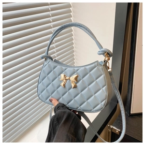 Détail du sac croissant matelassé bleu clair avec boucle papillon dorée décorative
