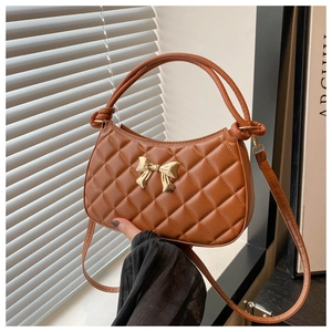 Détail d'un sac demi-lune marron matelassé avec un nœud papillon en métal doré