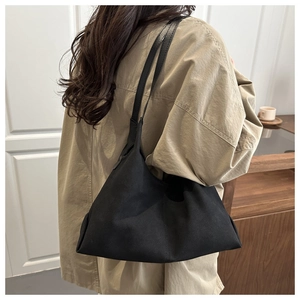 Detail of large black matte canvas tote bag with slim shoulder strap on female model