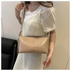 Gros plan du sac bandoulière beige avec coutures verticales et détail de nœud sur la sangle