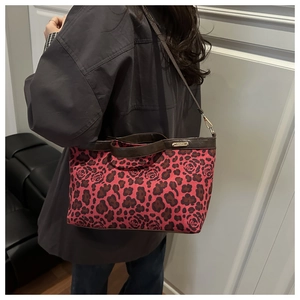 Close-up of leopard and rose print tote bag with brown leather straps and gold hardware