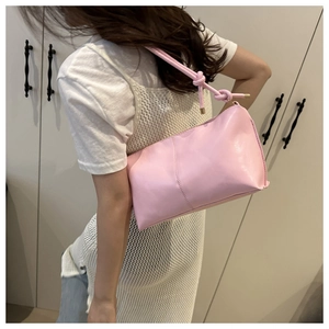 Detail of light pink shoulder bag with decorative strap knot and gold metal tips