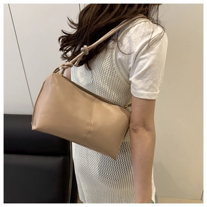Detailed close-up of khaki leather shoulder bag featuring unique knotted strap and sleek zipper