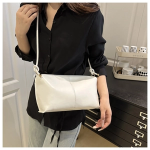Vue détaillée du sac en cuir crème avec bandoulière à nœuds et texture souple élégante