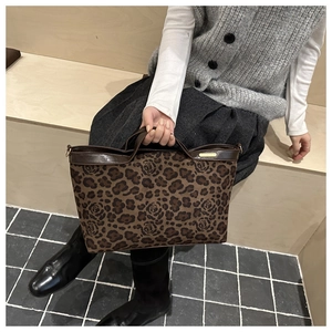 Detail view of leopard print tote bag with rose floral patterns and gold hardware