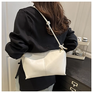Detail of white leather tote bag with knot strap design and elegant gold zipper hardware