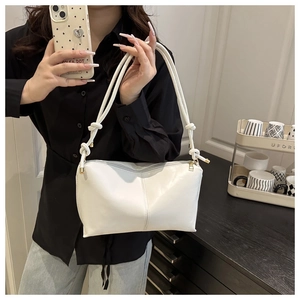Détail du sac sous l'aisselle en similicuir blanc avec bandoulière nouée sur modèle