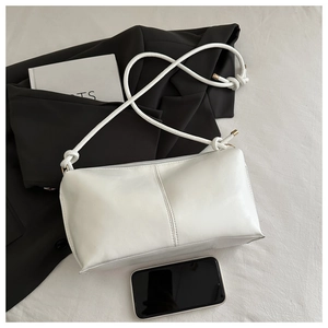 Close-up of white PU leather shoulder bag with vertical stitching and woven knot strap
