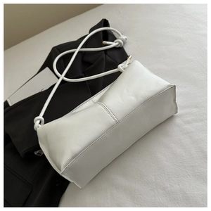 Top view of white leather shoulder bag with thick rope strap on a black blazer