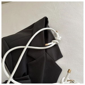 Close-up of white knotted rope shoulder strap with elegant gold metal cylinder caps