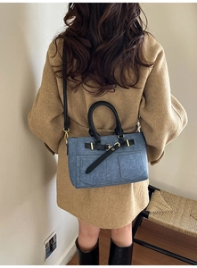 Dettaglio di borsa a spalla in denim blu con doppie tasche e manici in pelle nera