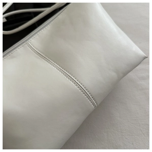 Detail view of white PU leather tote bag with silver zipper and fine double stitching