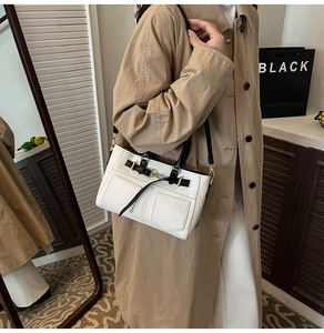 Dettaglio della borsa a spalla in pelle bianca con due tasche frontali e hardware dorato